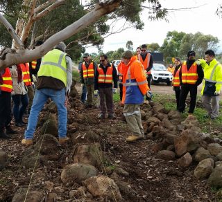 David Long instructing participants in dry stone walling techniques for historic basalt walls.