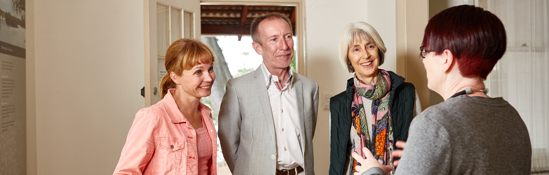 Three visitors two women and a man speak to a female curator