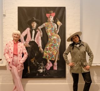 DJ Charlie Villas and her wife Nikita Majajas in front of the painting of them by artist Tania Wursig