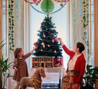 Girl and adult putting decorations on a Christmas Tree