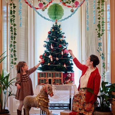 Girl and adult putting decorations on a Christmas Tree