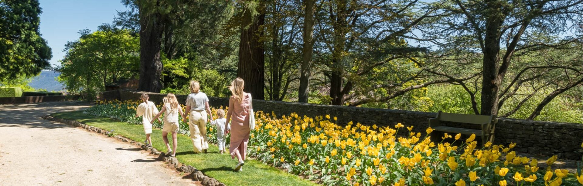 A young family and a grandmother walk down the drive at Everglades House  Gardens