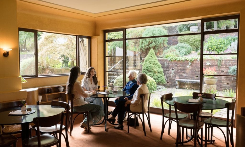 Two older women and two younger women chat while enjoying tea and scones. 