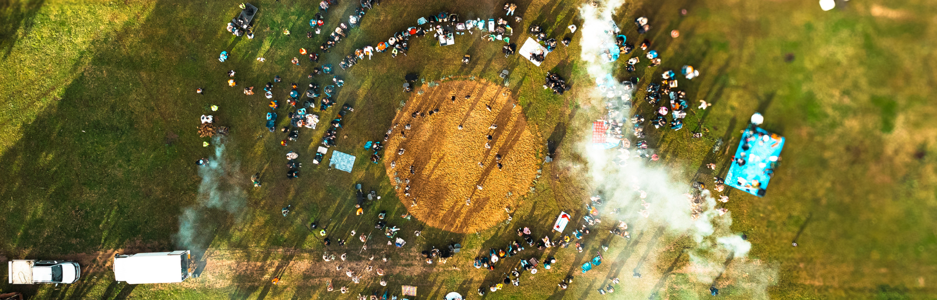An overhead shot of a community celebration there is a circular performance space in the centre that a growd is gathered around