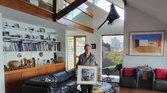 A woman standing in a Modern home holding a painting.