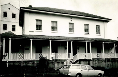 A black and white image of a Georgian house with a car parked in front