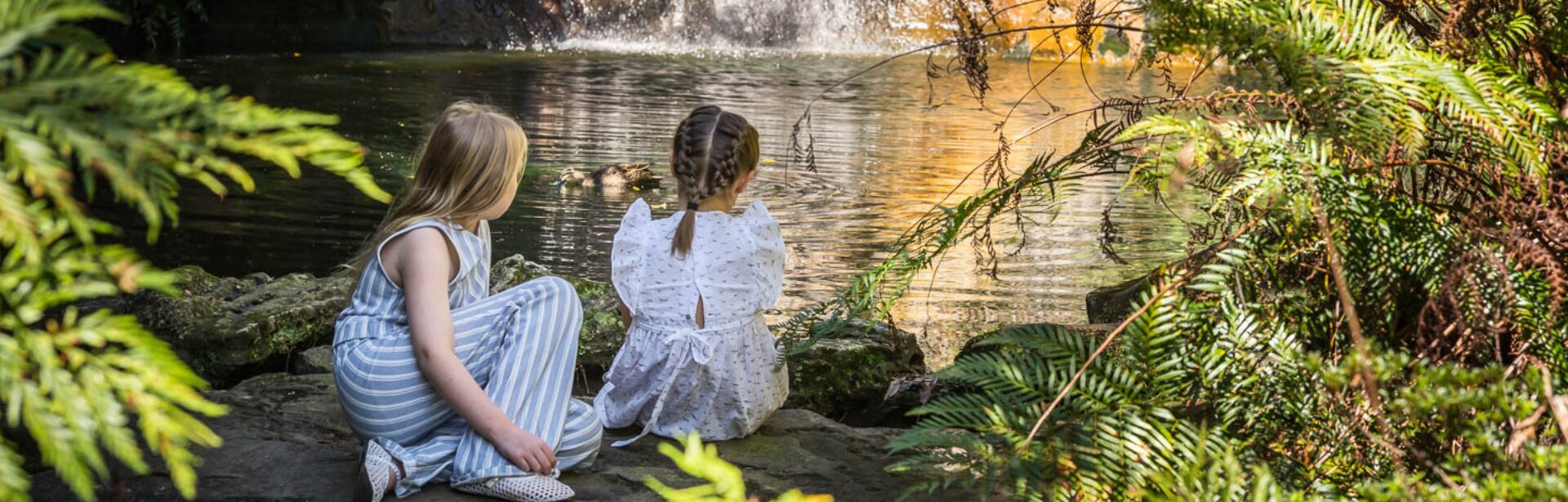 Two young girls in front of a waterfall at Everglades House Gardens