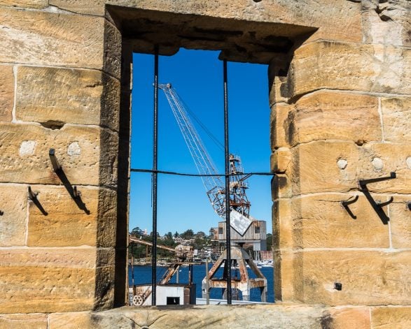 A window in a sandstone building reflecting Sydney Harbour