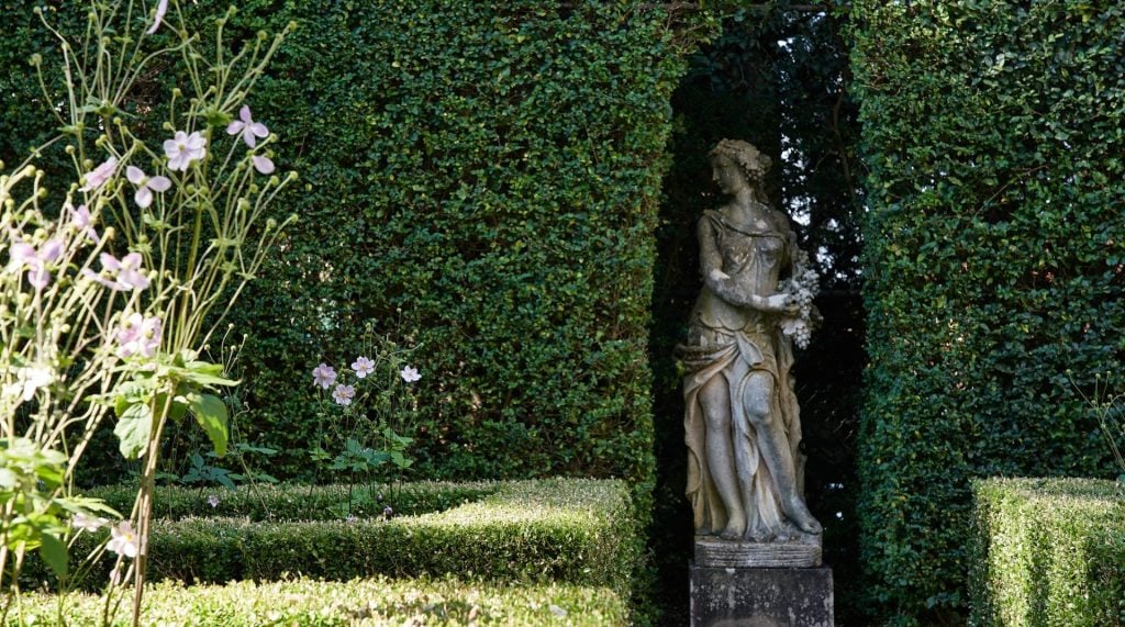 A formal garden featuring a graceful statue.