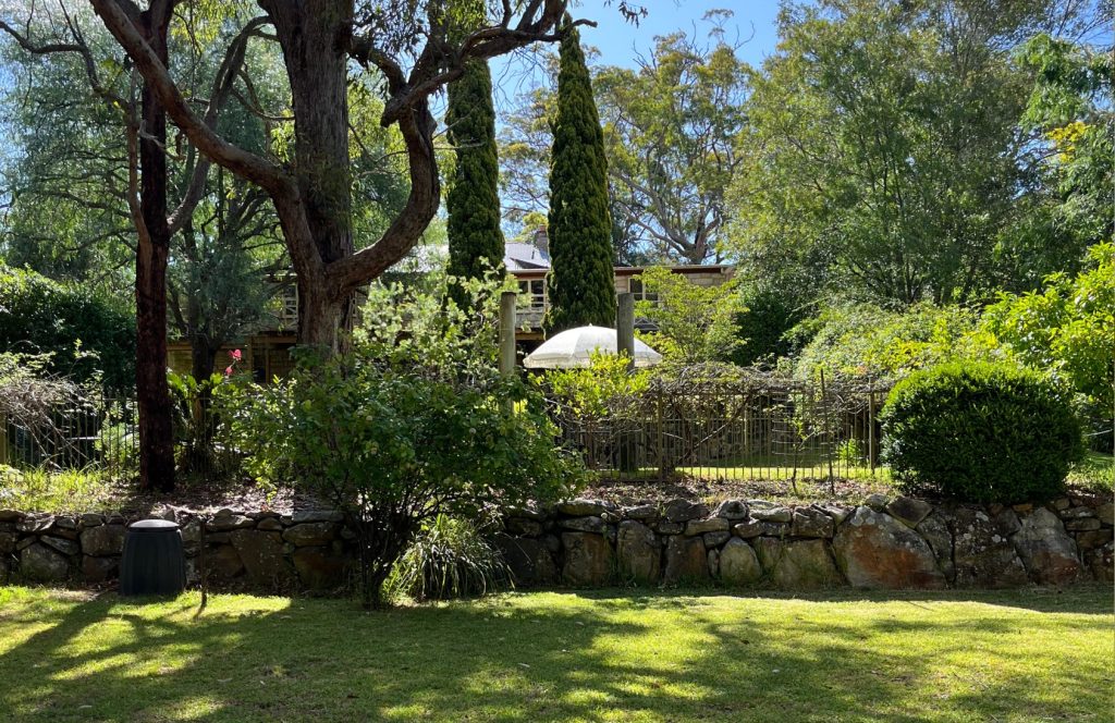 A sweeping expanse of lawn is looked down on by a house framed by formal Cyprus trees.