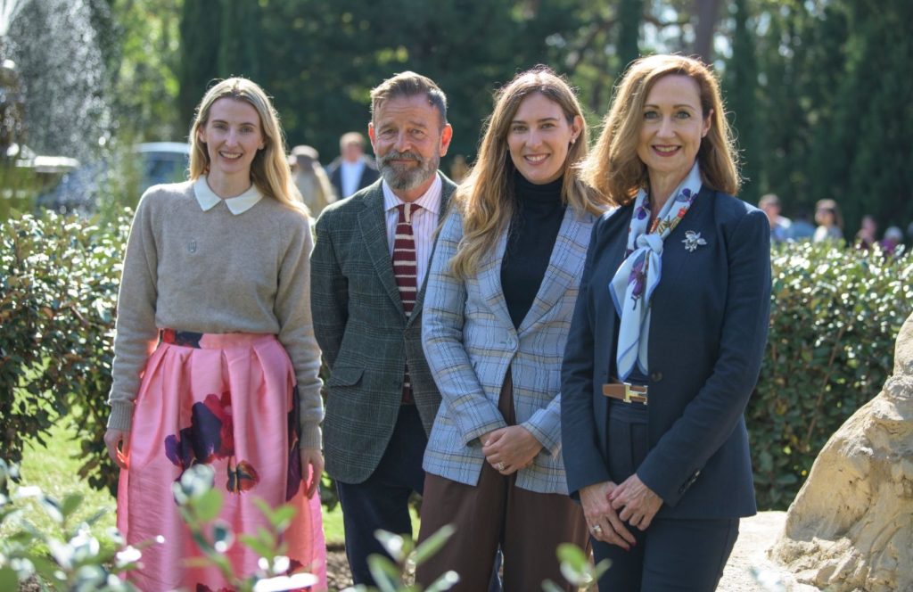 A group of smartly dressed people look to the camera smiling.